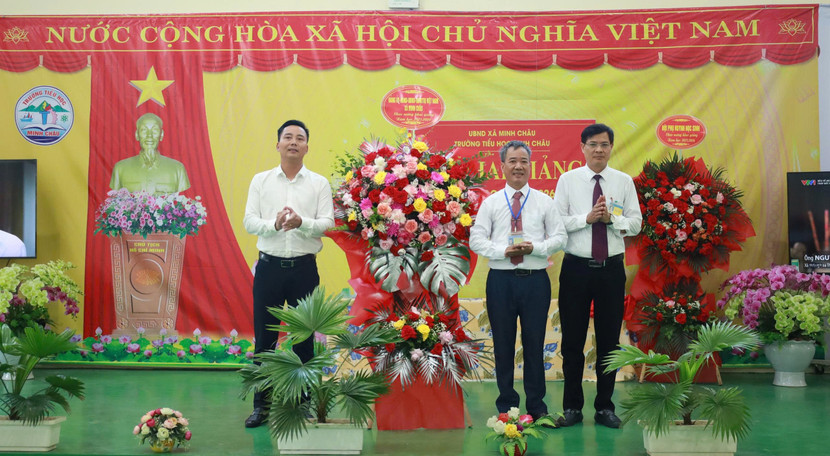 Đồng chí Nguyễn Đức Tiến, Bí thư Đảng ủy - Chủ tịch HĐND xã Minh Châu tặng lẵng hoa chúc mừng cô và trò trường Tiểu học Minh Châu