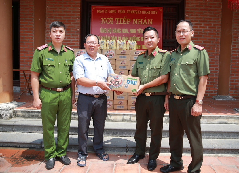 Trung tá Chu Quốc Dũng - Phó trưởng Ban Biên tập An ninh Thủ đô (thứ hai từ phải qua) trao quà cho đại diện chính quyền xã Thanh Thủy, Thanh Liêm, Hà Nam