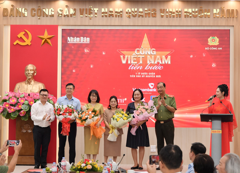 Tổng Biên tập Báo Nhân Dân, Chủ tịch Hội Nhà báo Việt Nam (bên trái) Lê Quốc Minh và Thiếu tướng Lê Hồng Hiệp - Phó Cục trưởng Cục Công tác chính trị Bộ Công an (bên phải) tặng hoa cho đại diện thương hiệu đồng hành Vietcombank - bà Đoàn Hồng Nhung, Thành viên Ban Điều hành, Giám đốc Khối Bán lẻ (thứ 3 từ trái sang) cùng các nhà tài trợ khác
