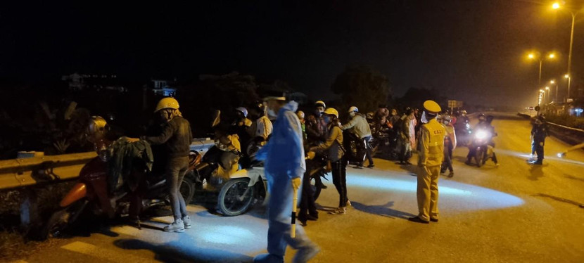 CSGT Công an Hà Nội hướng dẫn người dân xếp hàng để kiểm tra phòng chống dịch bệnh trước khi hướng dẫn họ lên Quốc lộ 32 về quê