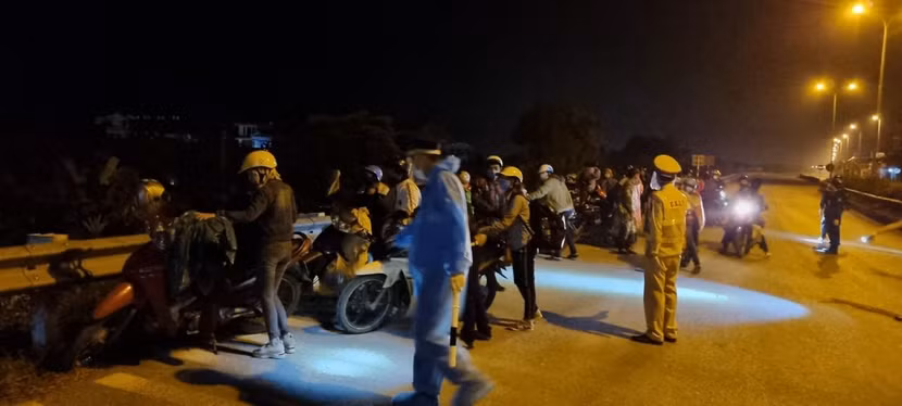 CSGT Công an Hà Nội hướng dẫn người dân xếp hàng để kiểm tra phòng chống dịch bệnh trước khi hướng dẫn họ lên Quốc lộ 32 về quê