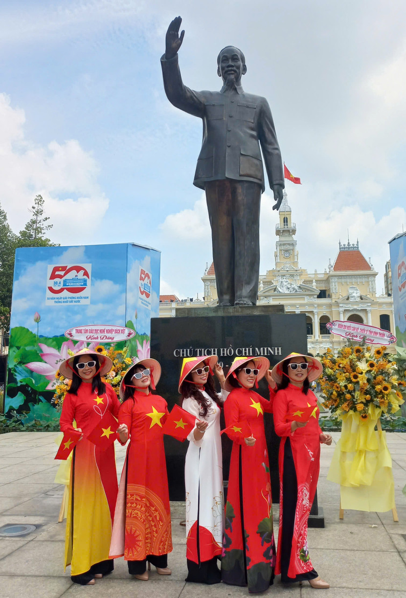 Phụ nữ chụp ảnh trước tượng đài Bác Hồ và trụ sở UBND TP.HCM (Ảnh: BÙI HÂN)