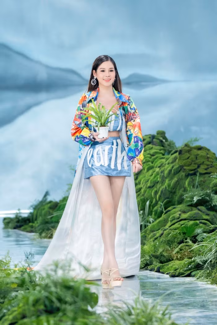 Thí sinh Nguyễn Hoài Linh cho biết ý tưởng in hai dòng chữ Healthy và Earth trên trang phục, chính là muốn nhắc nhở mọi người về thông điệp một trái đất cần khỏe mạnh. Cùng với nhóm bạn lên ý tưởng và thiết kế bộ trang phục, Hoài Linh tiết lộ chiếc áo khoác được làm từ tấm phông bạt nhựa, trong khi áo và váy hoàn toàn được làm từ vải tái chế…