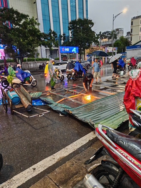 Một tấm biển quảng cáo bị kéo đổ văng ra đường, và lực lượng chức năng đã có mặt để xử lý