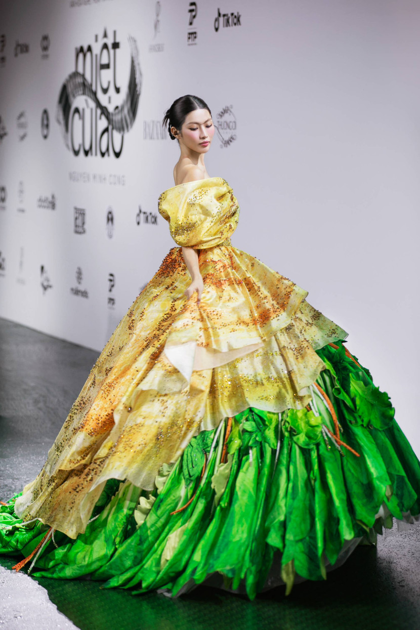 Á hậu – MC Chế Nguyễn Quỳnh Châu mở màn với trang phục “Bánh xèo”. Mang form váy bồng xòe với tone màu vàng chủ đạo của lớp bánh giòn và điểm nhấn với chi tiết rau, thiết kế “Bánh xèo” của Chế Nguyễn Quỳnh Châu đã khiến toàn bộ khán giả choáng ngợp bởi độ khủng và sự đầu tư, tỉ mỉ cho từng chi tiết