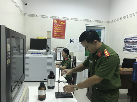 Cán bộ khoa học hình sự phân tích mẫu vật thu thập được ngoài hiện trường