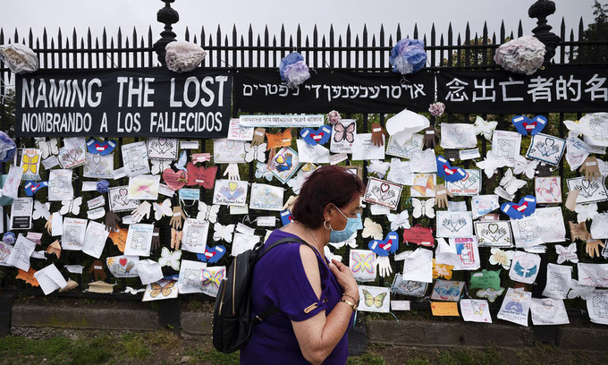 Một phụ nữ đi qua bức tường nghĩa trang tưởng niệm những người thiệt mạng vì đại dịch Covid-19 thành phố New York của Mỹ