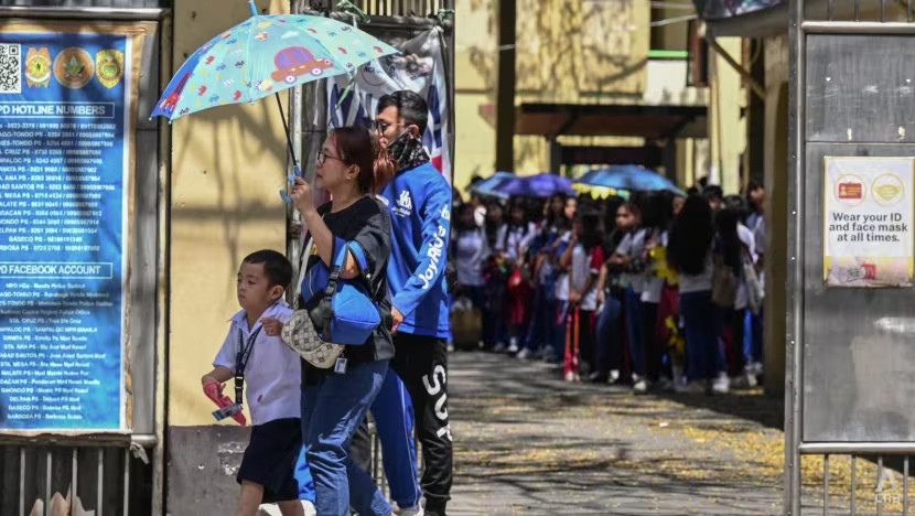 Rất đông học sinh đang đứng chờ phụ huynh đón trong thời tiết gần 40 độ C. Ảnh: AFP