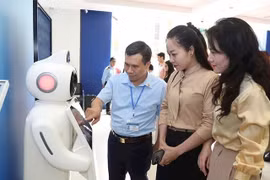 Cán bộ Trung tâm Phục vụ hành chính công Hà Nội hướng dẫn người dân sử dụng robot tư vấn các thủ tục hành chính. (Ảnh: Nhật Nam)