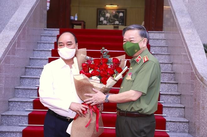 Đại tướng Tô Lâm, Ủy viên Bộ Chính trị, Bí thư Đảng ủy Công an Trung ương, Bộ trưởng Bộ Công an tặng hoa Chủ tịch nước Nguyễn Xuân Phúc