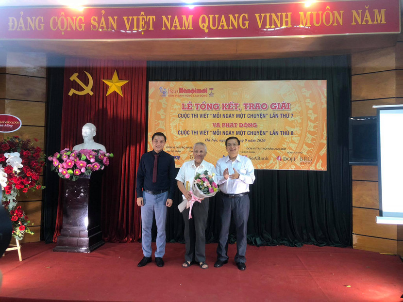 Tổng biên tập Báo Hà Nội Mới Nguyễn Hoàng Long (phải) cùng đại diện nhà tài trợ trao giải Nhất cho tác giả Mai Thế Chính
