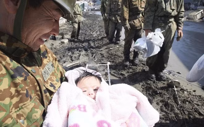 Thành viên Lực lượng Phòng vệ Nhật Bản bế em bé 4 tháng tuổi may mắn sống sót sau trận sóng thần ở thành phố Ishimaki, tỉnh Miyagi