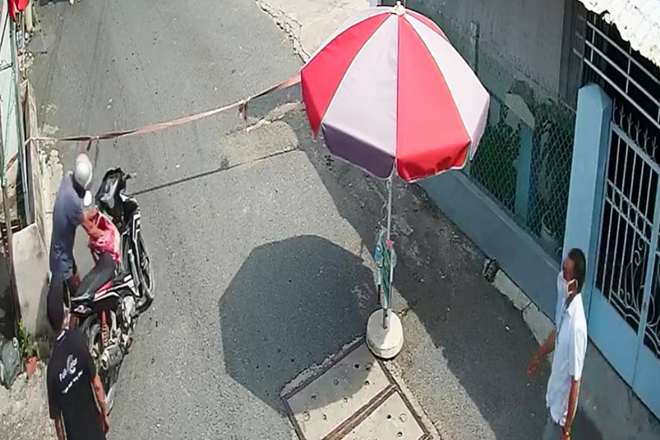 Đối tượng Hoàng Quang Trung (đội mũ bảo hiểm) bất ngờ rút dao trong cặp đuổi chém nhóm tình nguyện viên trực chốt (ảnh trích xuất từ camera an ninh) Đối tượng Hoàng Quang Trung (đội mũ bảo hiểm) bất ngờ rút dao trong cặp đuổi chém nhóm tình nguyện viên trực chốt (ảnh trích xuất từ camera an ninh)