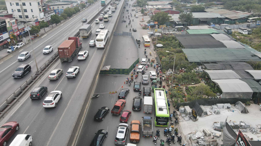 Dòng phương tiện nối đuôi nhau qua khu vực rào tôn, trong khi một bên đường có phần đất đang bị sử dụng sai mục đích để kinh doanh cây cảnh
