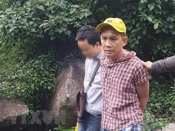 Nghi phạm Lê Trường Thành (áo kẻ) bị bắt giữ. Ảnh: TTXVN