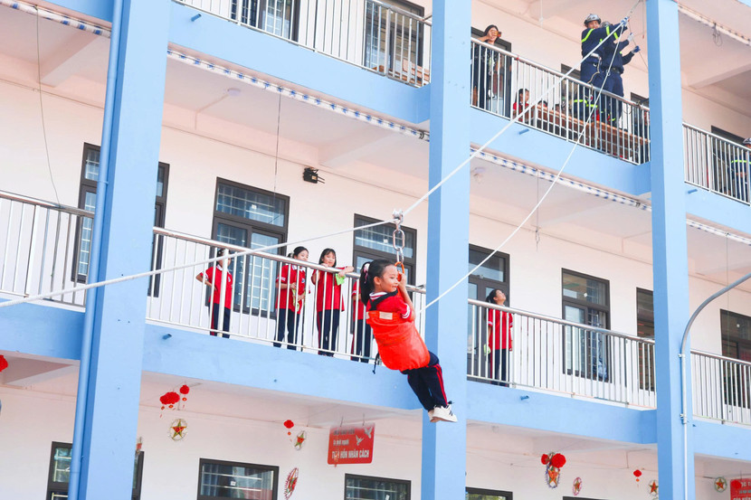 Dưới sự hướng dẫn tận tình của các cán bộ chiến sỹ, các em học sinh thích thú tham gia trải nghiệm thực hành thoát nạn bằng cầu dây nghiêng từ tầng cao xuống đất