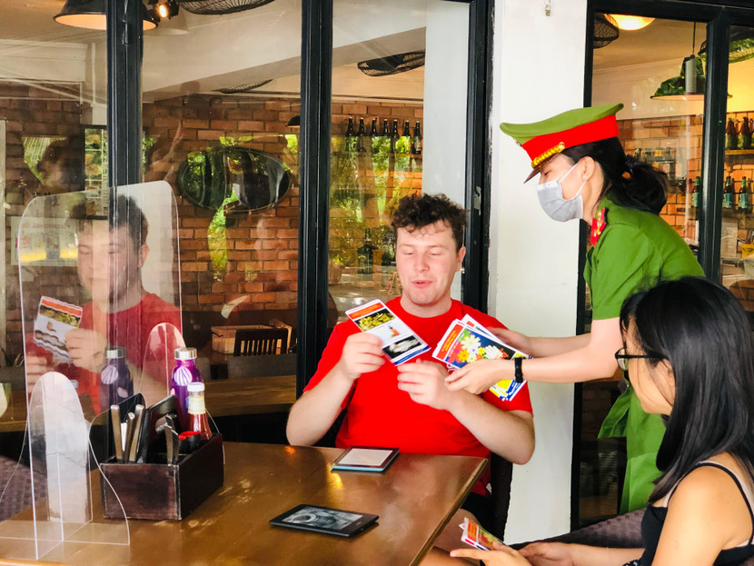 Nữ CBCS phòng Cảnh sát điều tra tội phạm về ma túy tự tin giao tiếp với người nước ngoài tuyên truyền về phòng, chống ma túy trong tờ rơi