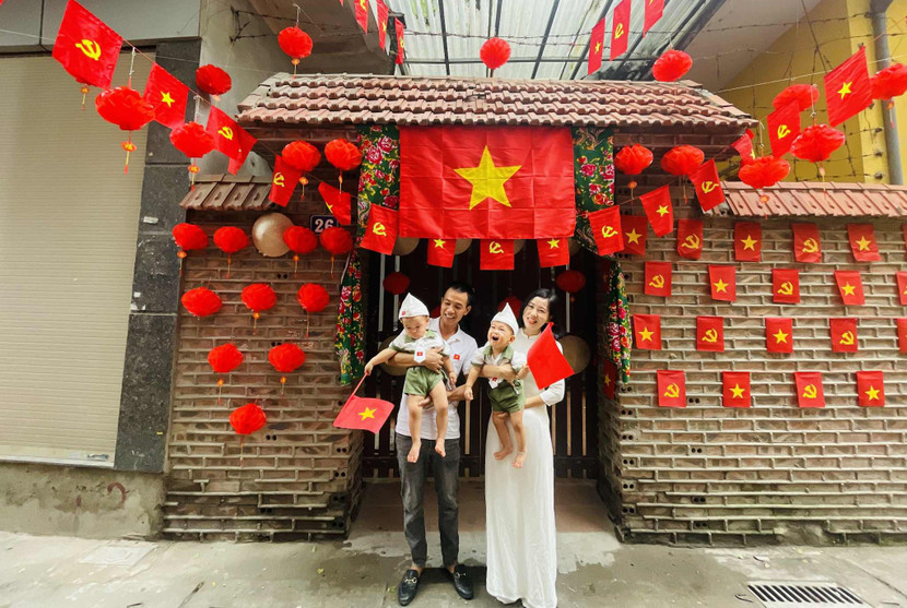 Gia đình anh Thuận Đạt trước ngôi nhà rợp cờ đỏ sao vàng với niềm tự hào