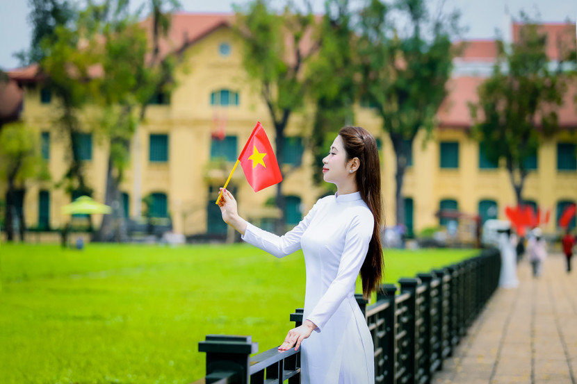 Trên tay lá cờ Tổ quốc - biểu tượng thiêng liêng đặc biệt của dân tộc Việt Nam. Nền cờ màu đỏ tượng trưng dòng máu đỏ, màu của nhiệt huyết khiến gương mặt của thiếu nữ Hà thành hiện rõ ý chí, niềm tin