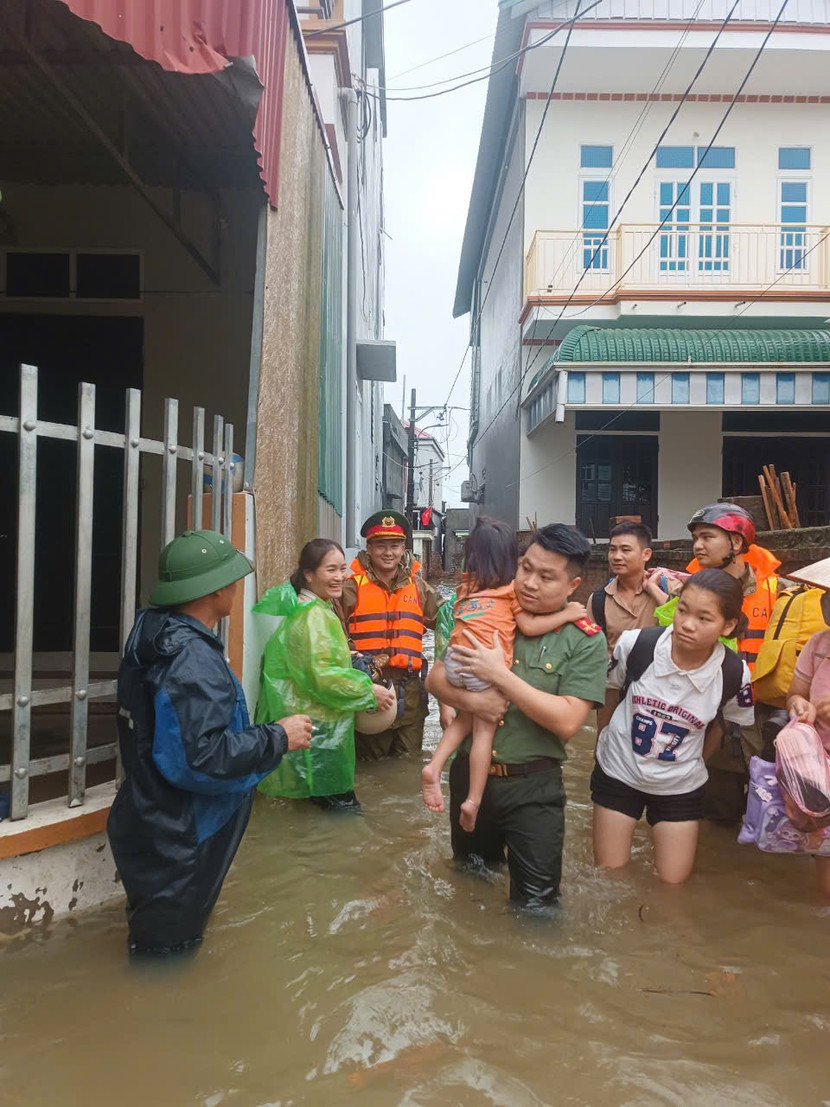 Cán bộ Công an huyện Quốc Oai đưa những em nhỏ di chuyển khỏi khu vực ngập sâu