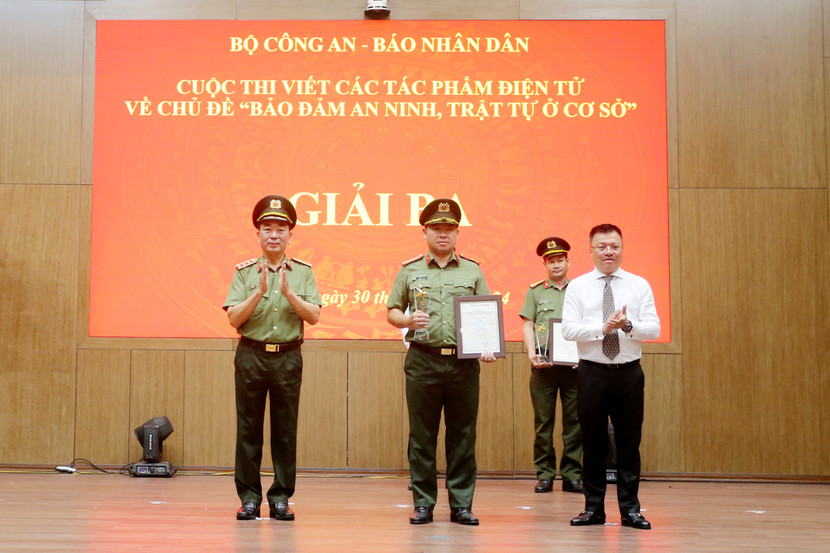Thượng tướng Trần Quốc Tỏ, cùng Tổng Biên tập Báo Nhân dân Lê Quốc Minh trao giải Ba. Thay mặt nhóm tác giả Chuyên đề An ninh Thủ đô, Thiếu tá Đỗ Trần Quân, Trưởng Ban Thư ký biên tập nhận giải