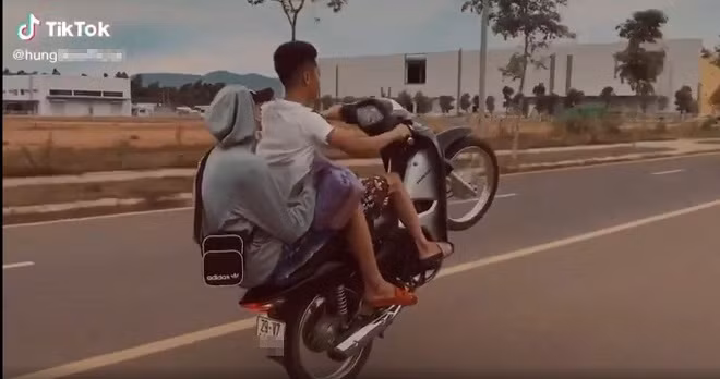 Hình ảnh hai nam thanh niên điều khiển xe máy bằng một bánh, không đội mũ bảo hiểm Hình ảnh hai nam thanh niên điều khiển xe máy bằng một bánh, không đội mũ bảo hiểm