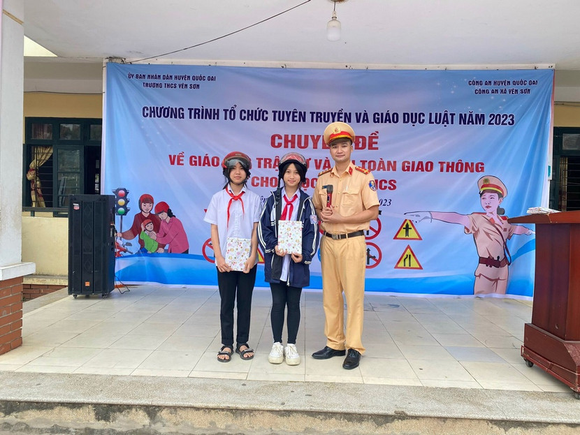 Cán bộ Đội Cảnh sát giao thông trật tự Công an huyện Quốc Oai tặng quà cho các em học sinh tham gia hỏi đáp kiến thức pháp luật về an toàn giao thông