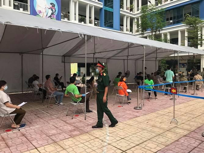 Công dân xếp hàng ngồi chờ tiêm đảm bảo giãn cách tại điểm tiêm trường Tiểu học Thịnh Hào, phường Ô Chợ Dừa