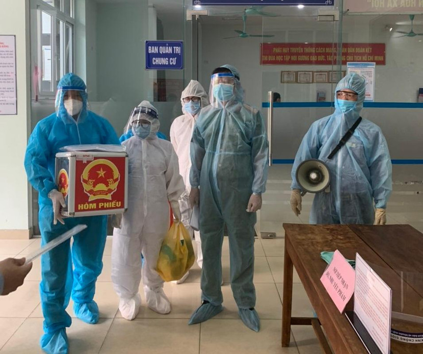 Lực lượng chức năng mang hòm phiếu đến nhà để cử tri đang cách ly thực hiện bỏ phiếu