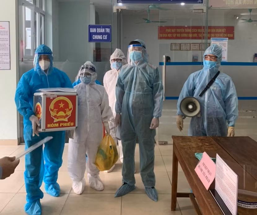 Lực lượng chức năng mang hòm phiếu đến nhà để cử tri đang cách ly thực hiện bỏ phiếu