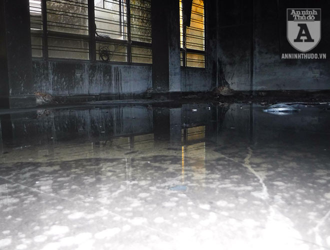 Nước chữa cháy loang loáng trên nền nhà, trở nên đen vì nhiều tro bụi