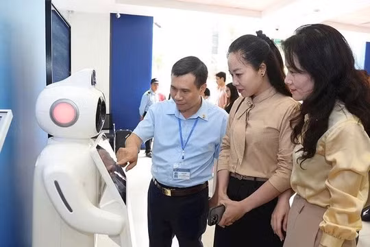Cán bộ Trung tâm Phục vụ hành chính công Hà Nội hướng dẫn người dân sử dụng robot tư vấn các thủ tục hành chính. (Ảnh: Nhật Nam)
