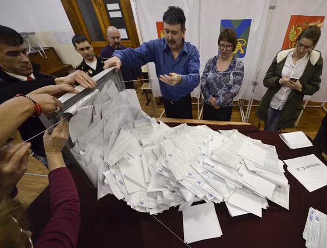 Các thành viên trong tổ bầu cử địa phương đổ hòm phiếu ra để kiểm