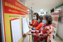 Thủ đô Hà Nội đang tập trung cao độ để thực hiện mục tiêu kép, vừa bảo đảm an toàn, bình yên cho nhân dân, vừa bảo đảm thành công ngày bầu cử (Trong ảnh: Người dân theo dõi danh sách niêm yết cử tri tại trụ sở HĐND, UBND phường Hàng Đào, quận Hoàn Kiếm, Hà Nội). Ảnh: LAM THANH