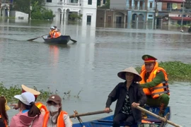 Dùng thuyền tiếp tế thực phẩm cho người dân bị cô lập do mưa bão gây ngập úng ở giáo xứ Đồng Chiêm