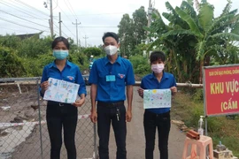 Hai nữ tình nguyện viên trẻ vừa trực chốt kiểm soát dịch vừa vẽ tranh cổ động