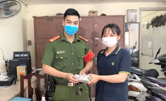 Em Kiều Anh giao số tiền gần 200 triệu đồng nhặt được cho Công an phường 14 (quận Bình Thạnh) để tìm người đánh rơi. Ảnh: Dân Trí
